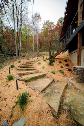 Un chemin de pierres mène à un bâtiment dont l’extérieur est en bois et la base en pierre.