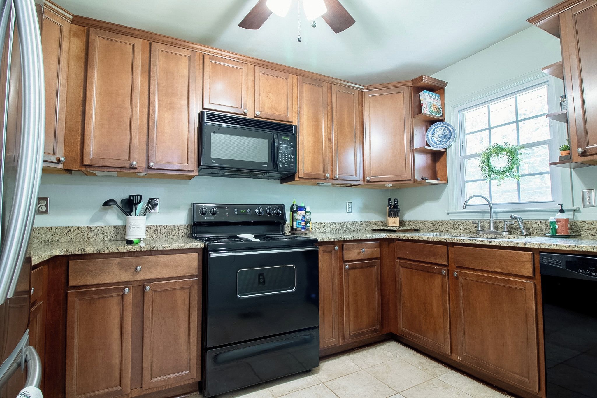 A kitchen with wooden cabinets, a black microwave, a stove, and a dishwasher.
