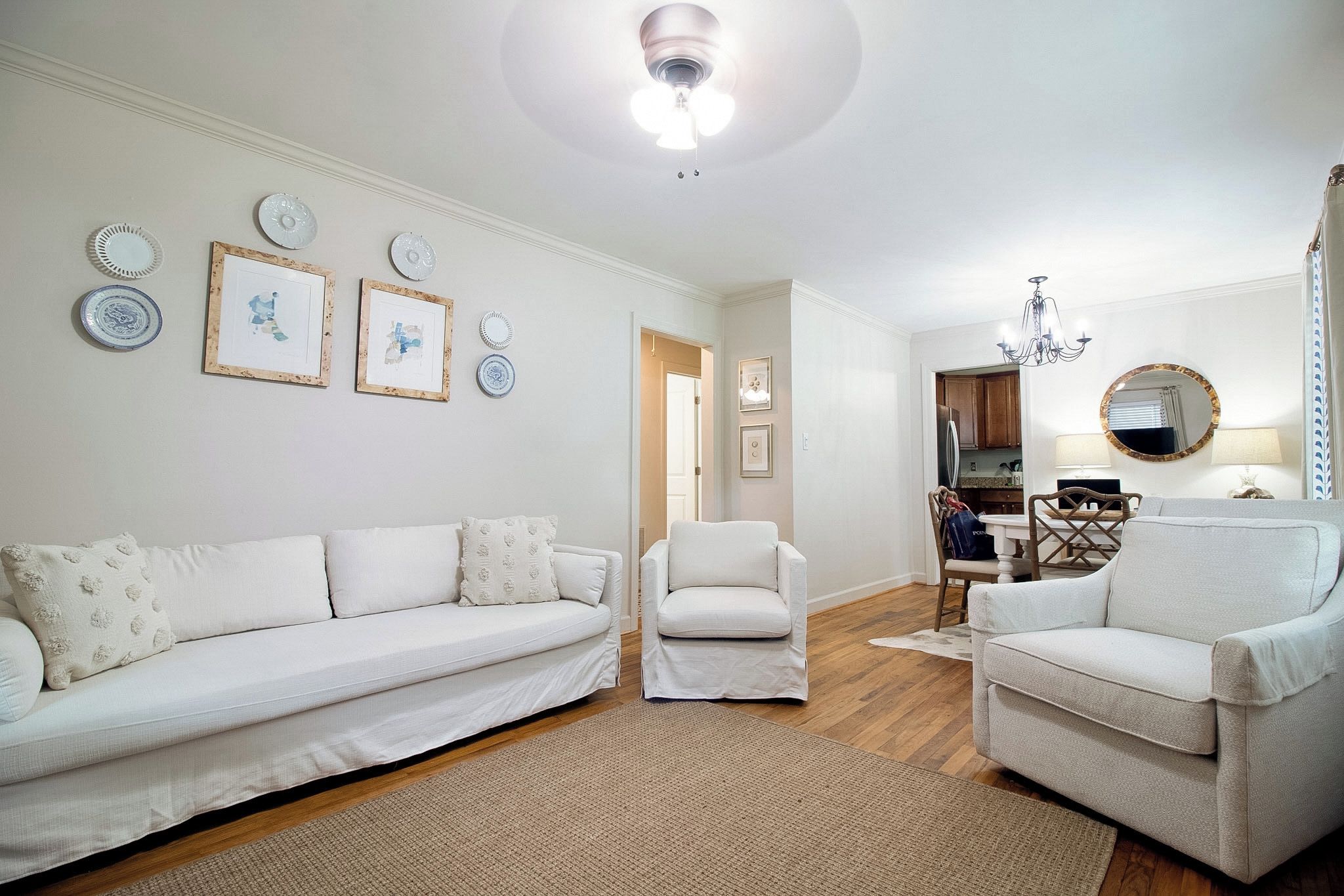 Una sala de estar con un sofá blanco, dos sillones, una mesa de centro y un candelabro.