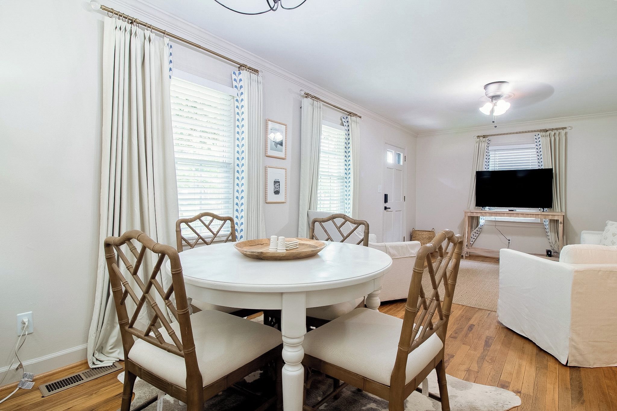 A dining area with a round table and chairs, a television, and a sofa in a living room.