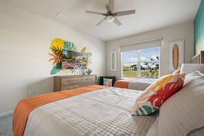 A bedroom with a bed, a dresser, a ceiling fan, and a window with blinds. - Pool Table, Air Hockey, Swing, Basketball, Themed Rooms: Coastal Cove Retreat (Clermont)