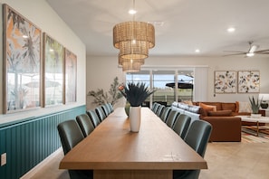 Un comedor espacioso con una larga mesa de madera, múltiples sillas e una gran lámpara colgante de fibras.