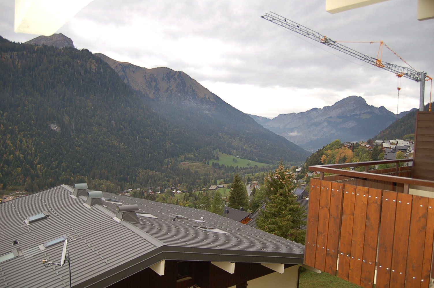 Blick auf Berge von einem Gebäude mit geneigtem Dach und einem Holzzaun.