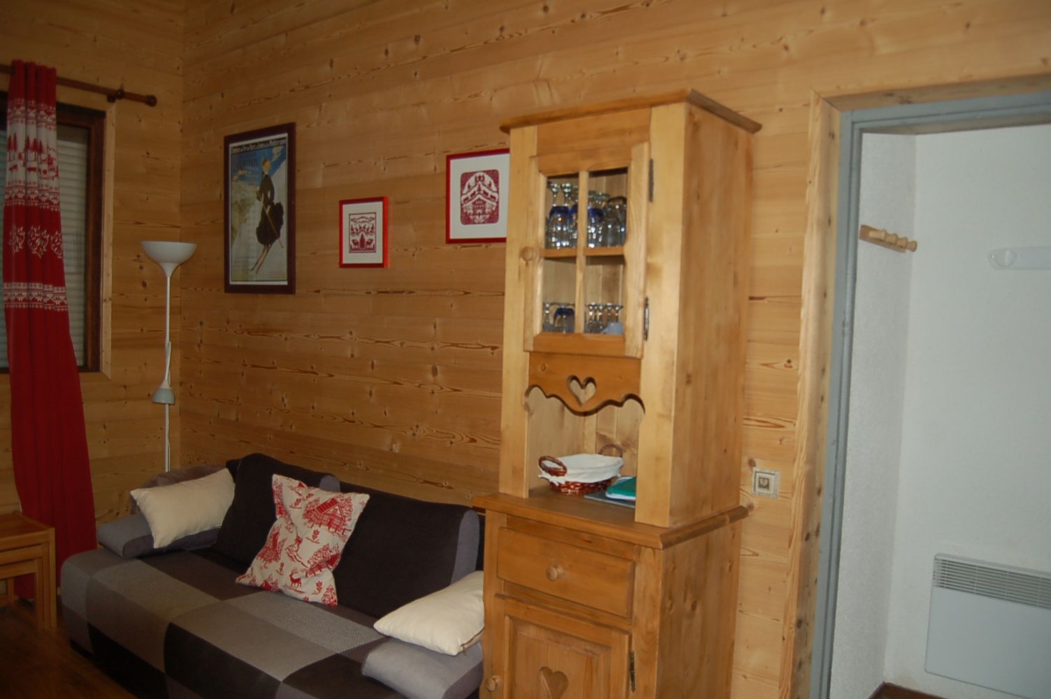 Ein Holzinterieur mit einer Couch, einem Schrank mit Glastüren und gerahmten Bildern an der Wand.