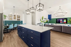 A modern kitchen with a central island, built-in appliances, and pendant lighting. - TWO full houses with a private pool, hot tub, gym, sauna, massage chair, cold plunge, movie projector, astroturf, axe throwing, corn hole and other lawn games! Unwind in this relaxing Paradise Oasis and let your worries drift away! (Austin)