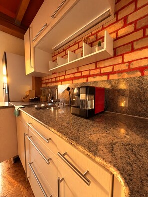 A kitchen with granite countertops, stainless steel appliances, and a brick wall. - Vrbo Property (Basel)