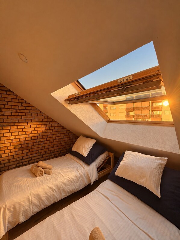 A room with two beds, a skylight, and a brick wall. - Vrbo Property (Basel)