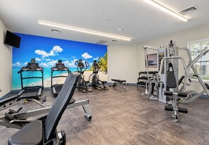 Un gimnasio con cintas de correr, elípticas, una banca y equipo de levantamiento de pesas.