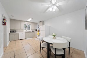 A modern kitchen with white cabinets, a microwave, and a dining area with a round table and chairs. - 4BR House Near FSU, Pet-Friendly (Tallahassee)