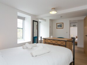 Une chambre à coucher avec un lit, un bureau, une chaise et une fenêtre.