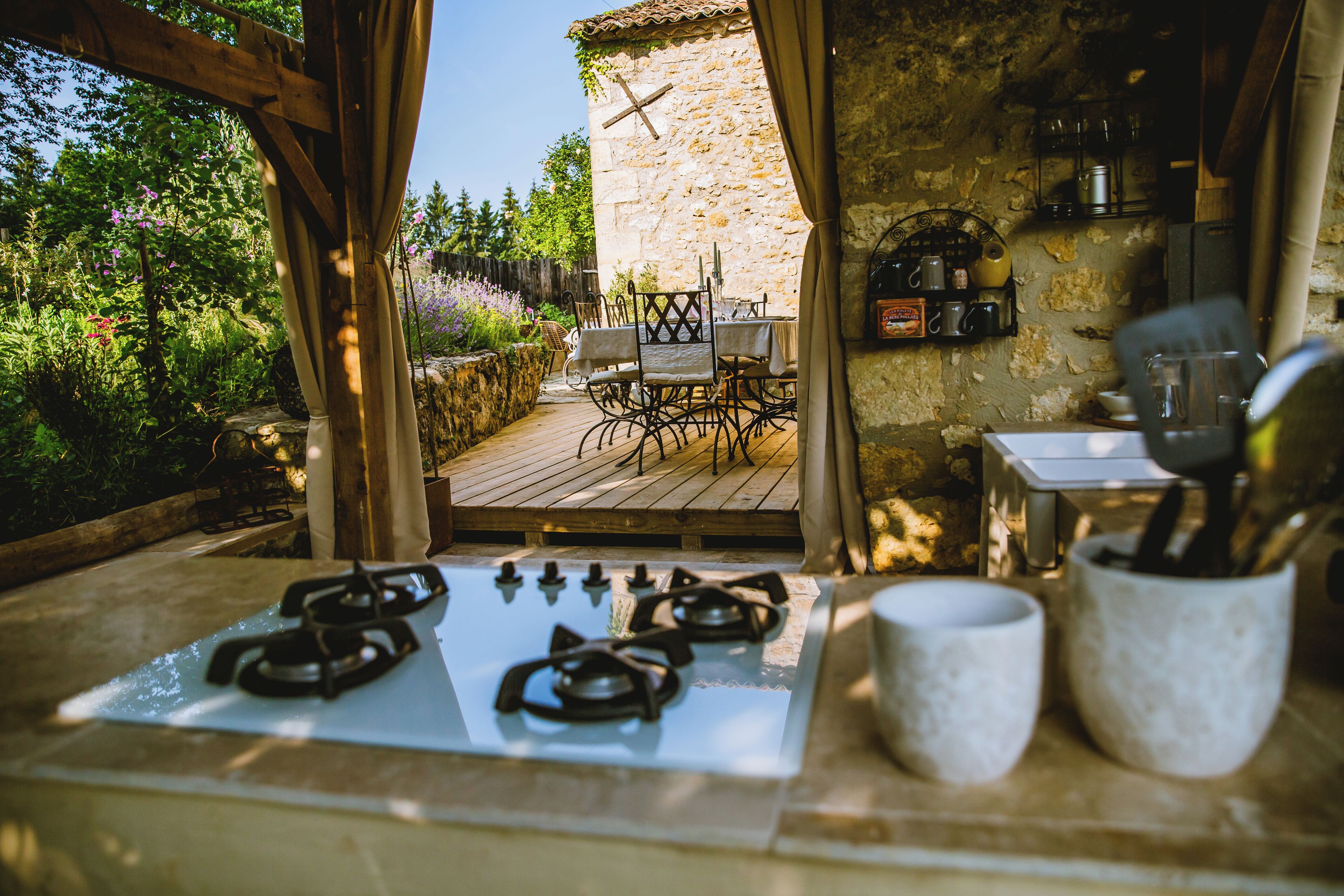 An outdoor kitchen area with a gas stove, outdoor seating, and stone walls.