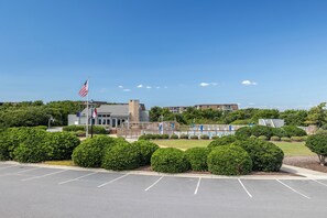 A building with a flagpole, a swimming pool, and a parking lot. - Tar Landing Villas 306 - 3BR 2 BA - Oceanview Condo in Atlantic Beach (Atlantic Beach)