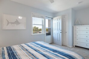 A bedroom with a bed, a dresser, a door, and a window. - Tar Landing Villas 306 - 3BR 2 BA - Oceanview Condo in Atlantic Beach (Atlantic Beach)