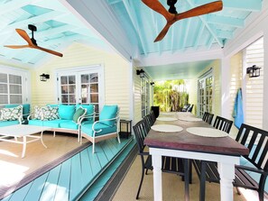 A covered porch with a dining table and chairs, a sofa with cushions, and ceiling fans. - Historic Seaport Retreat with Private Heated Pool & Guest Cottage (Key West)