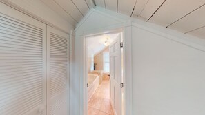 A hallway with a white door leading to a bathroom with a bathtub and a window. - Historic Seaport Retreat with Private Heated Pool & Guest Cottage (Key West)