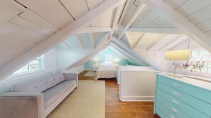 A bedroom with a sloped ceiling, a bed, a dresser, and a window. - Historic Seaport Retreat with Private Heated Pool & Guest Cottage (Key West)
