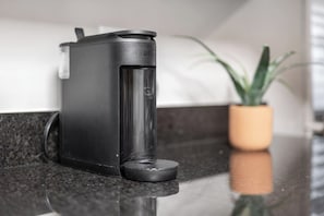 Eine schwarze elektrische Wasserwaage steht auf einer Küchenarbeitsplatte, im Hintergrund steht ein Topfpflanze.