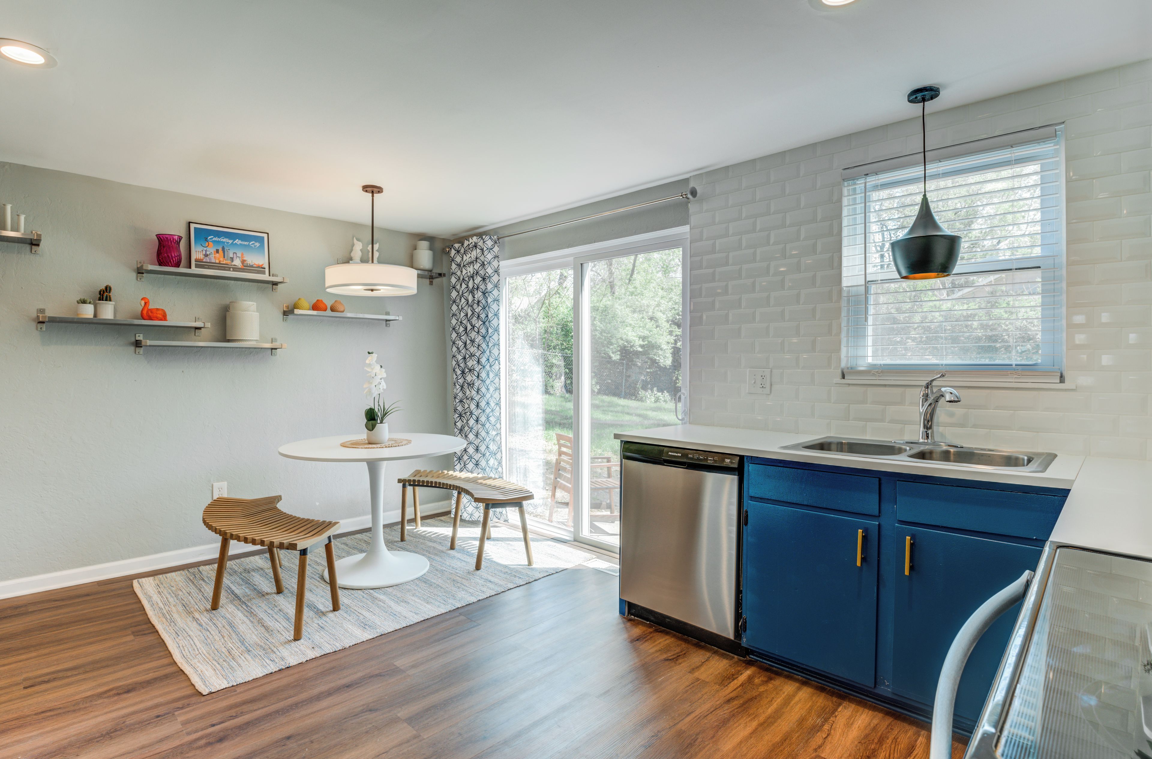 A modern kitchen with a dishwasher, blue cabinets, and a dining area with a round table and chairs.