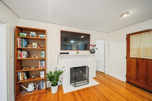 Ein Wohnzimmer mit Kamin, Bücherregal und Blumentopf.