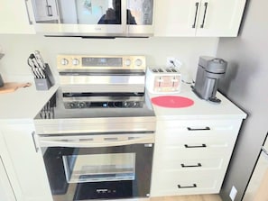 Eine kleine Küche mit integriertem Backofen, Mikrowelle und Kaffeemaschine.