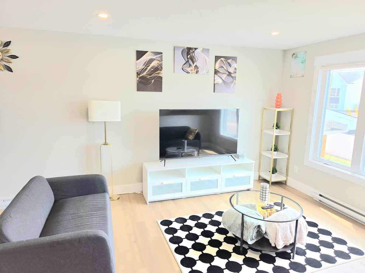 Un salon moderne avec un canapé, un téléviseur à écran plat, une table basse et un tapis à motifs.