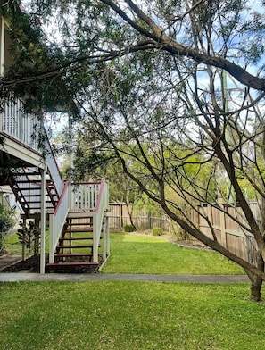 A residential property with a wooden deck, a staircase, and a well-maintained lawn.