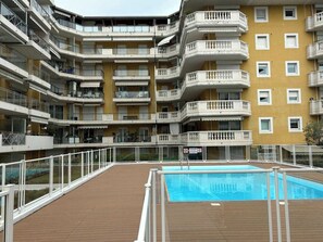 A multi-story residential building with balconies, a swimming pool, and a wooden deck. - Charming Studio With Balcony & Pool -heart of Nice (Nice)