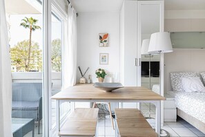 A modern bedroom with a bed, bedside table, lamp, and a view of the outdoors. - Charming Studio With Balcony & Pool -heart of Nice (Nice)