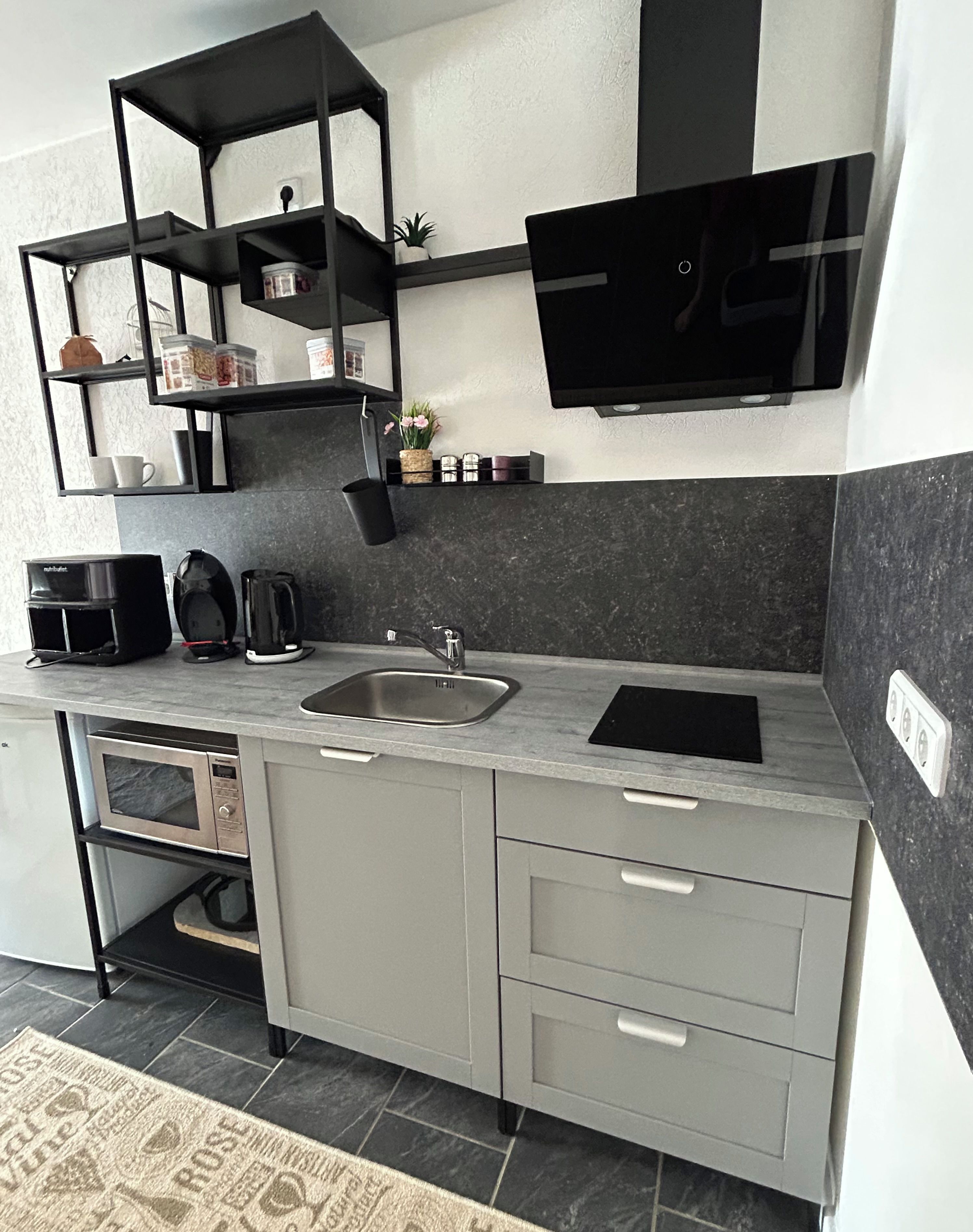 Una cucina moderna con forno a microonde integrato, macchina del caffè e lavello.