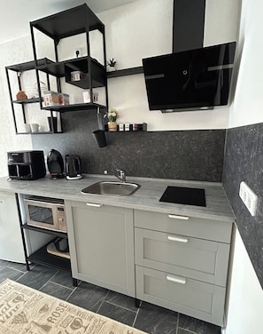 A modern kitchen with a built-in microwave, a coffee maker, and a sink.