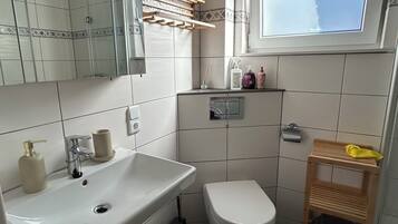 Un baño moderno con un espejo grande, un lavamanos, un inodoro y una cabina de ducha.