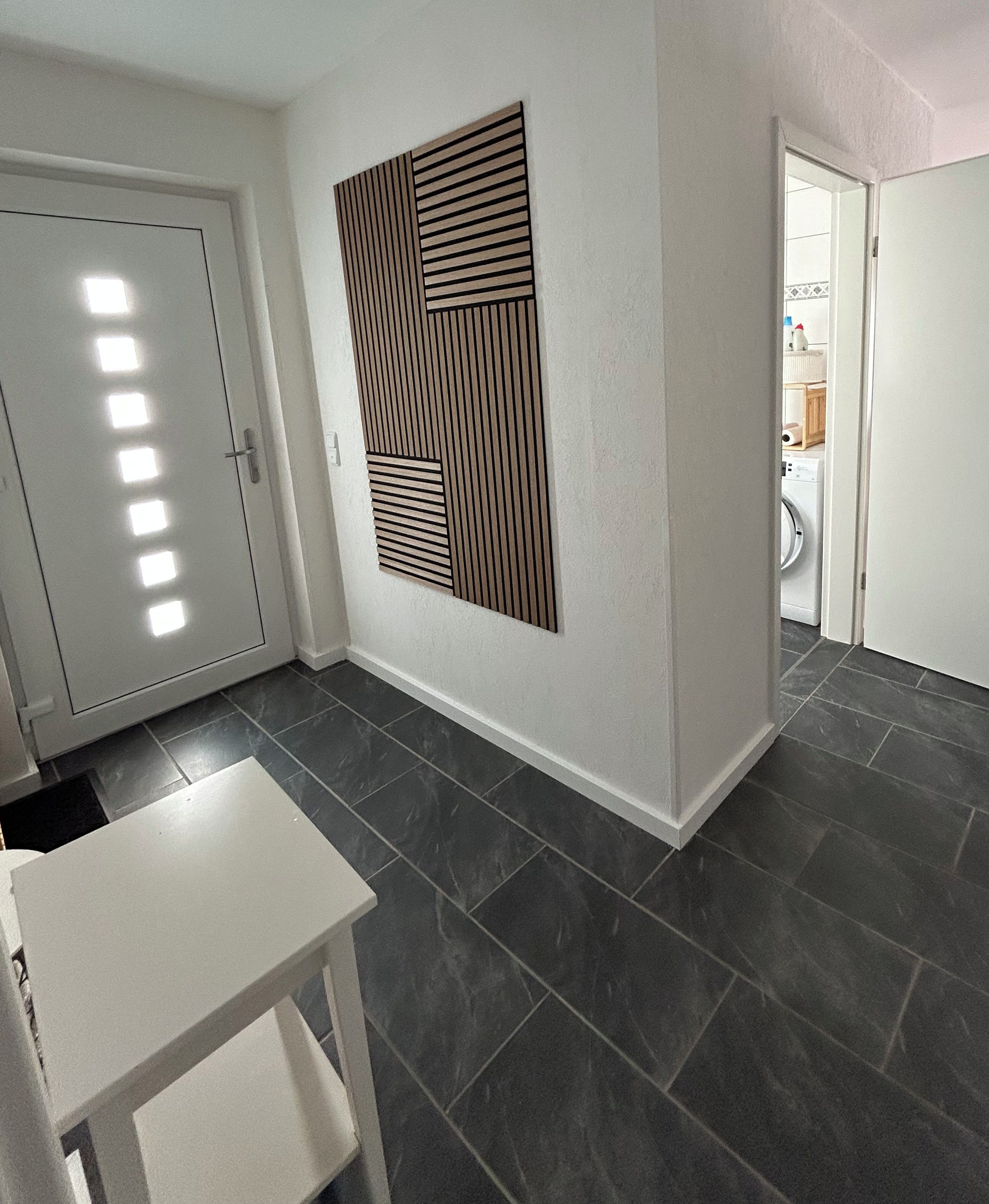 Ein Zimmer mit einer weißen Tür, einem weißen Tisch und einem Wandlüfter.