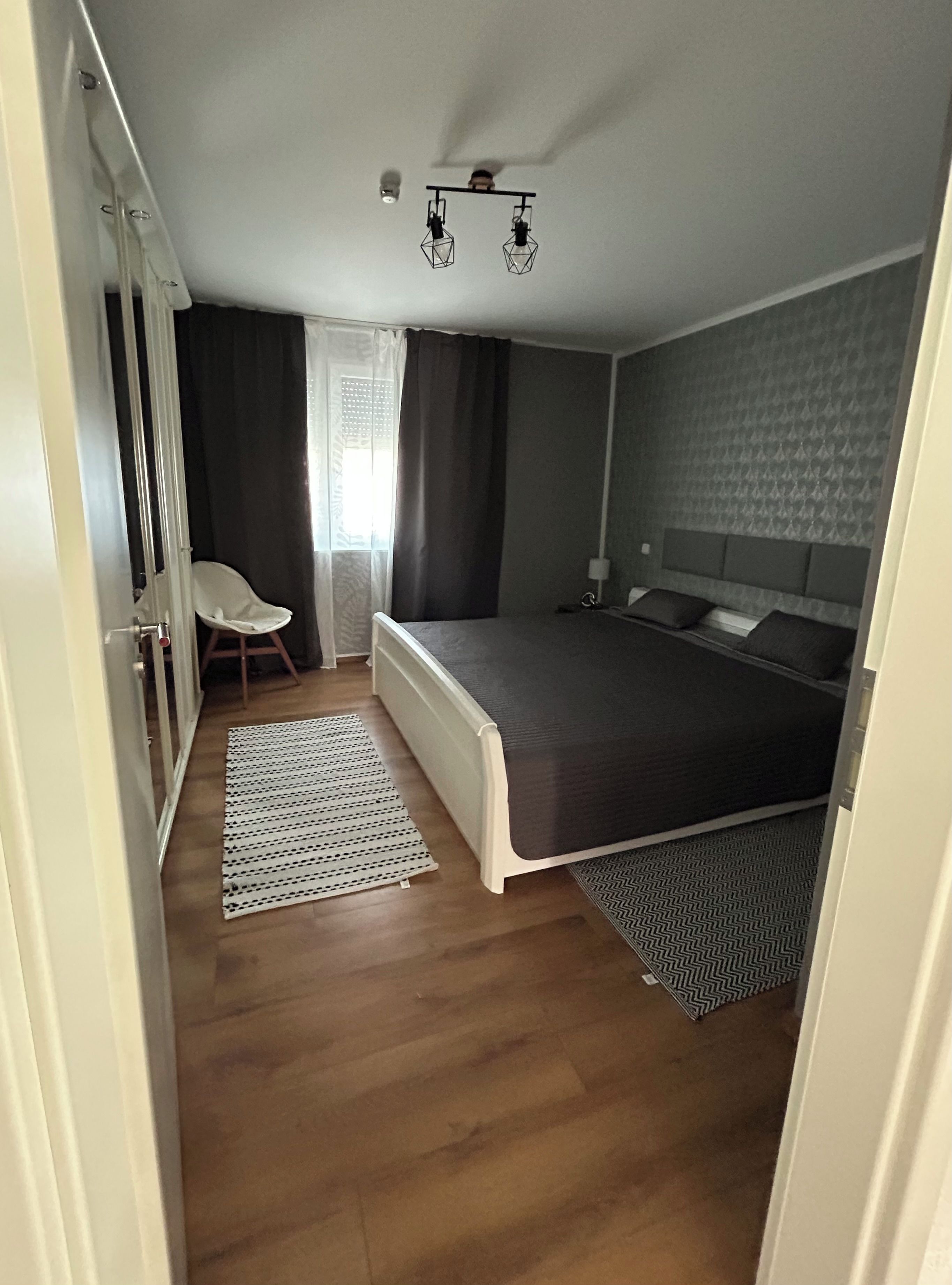 Un dormitorio con una cama, una silla, un radiador y un ventilador de techo.