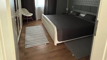 Un dormitorio con una cama, una silla, un radiador y un ventilador de techo.