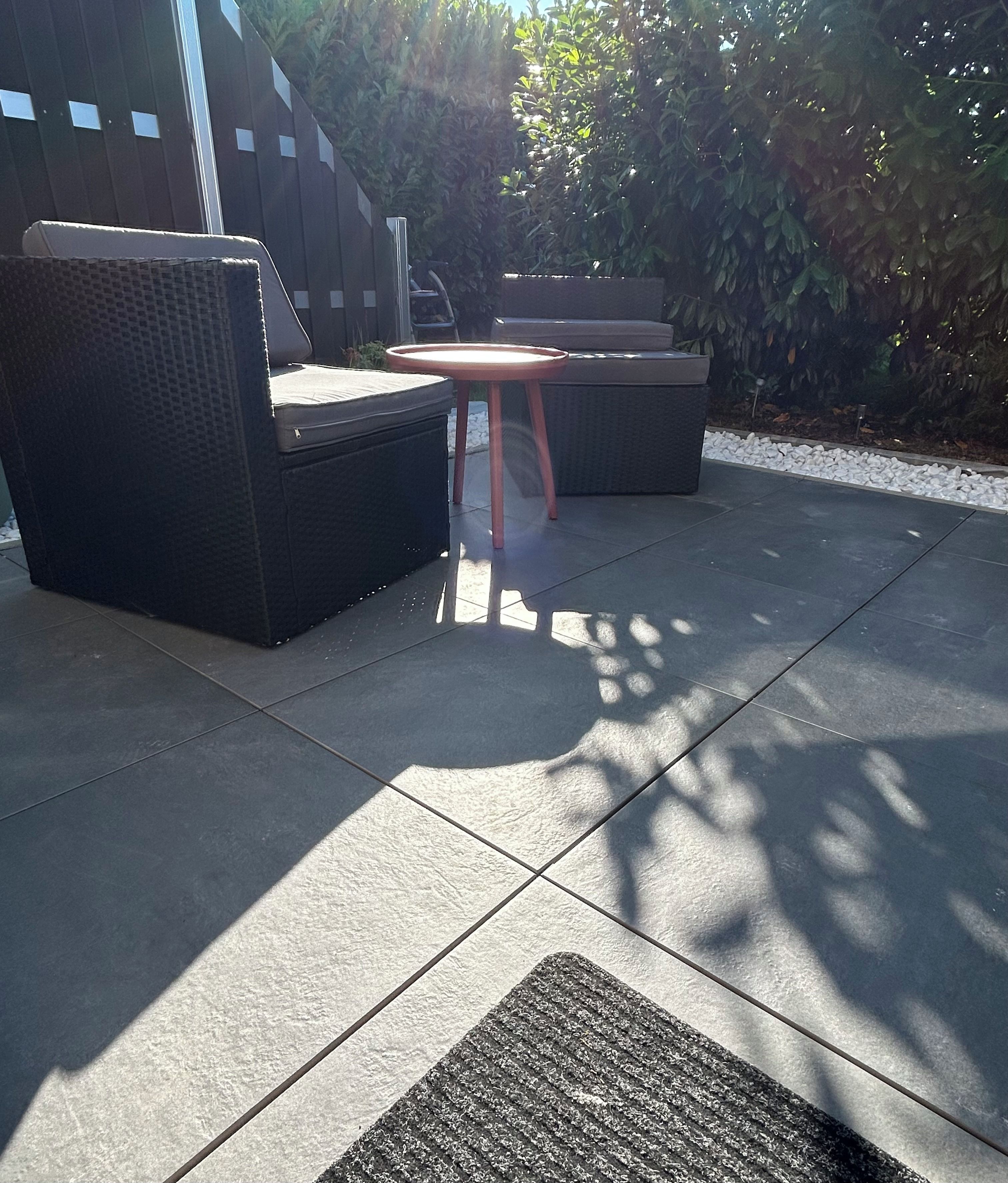 Un área de estar al aire libre con una mesa redonda y dos sofás.