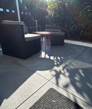 An outdoor seating area with a round table and two sofas.