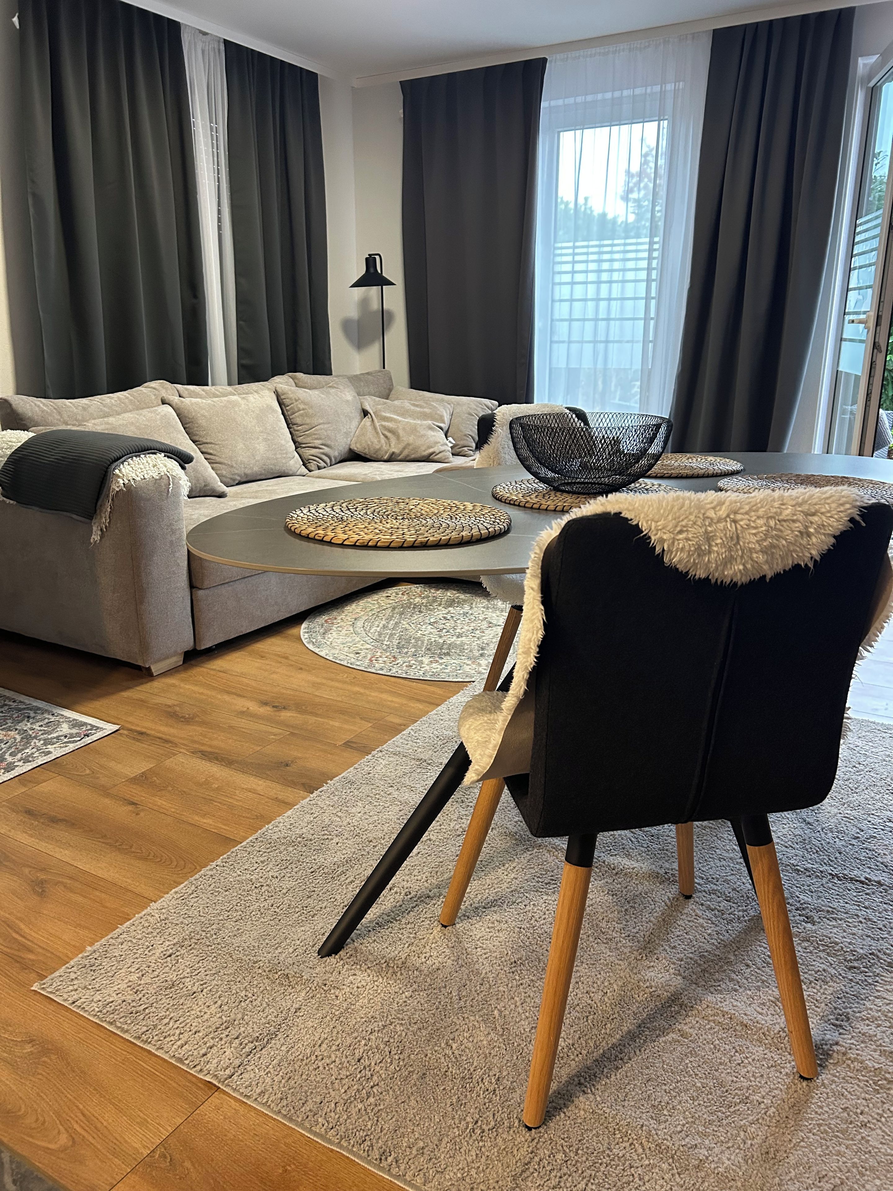Un salon moderne avec un canapé gris, un fauteuil noir et une table basse ronde.