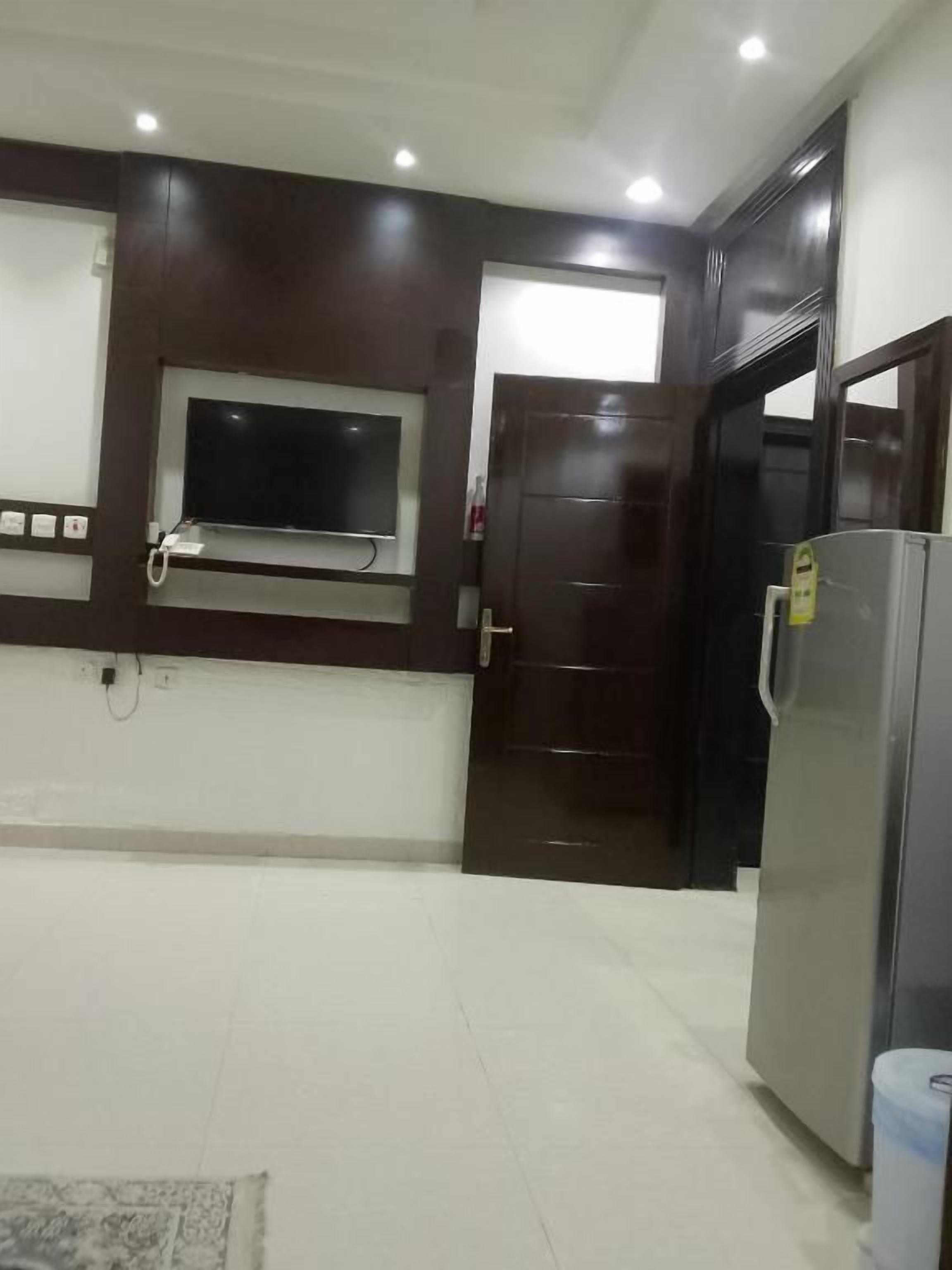 A kitchen with a built-in TV, a refrigerator, and a door leading to another room.