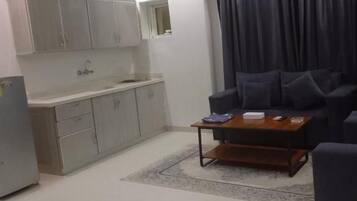 Una sala de estar moderna con un sofá, una mesa de centro y una zona de cocina con armarios y un lavabo.