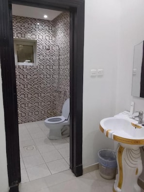 A bathroom with a toilet, a sink, and a shower. - aman home 1 for servied apartment  (Al-Khaleej District)