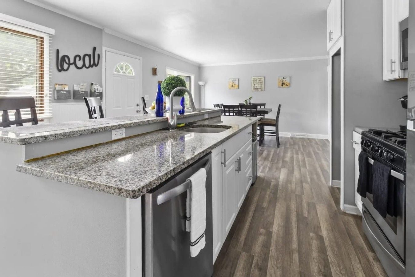 A modern kitchen with granite countertops, a stainless steel sink, and a built-in oven.