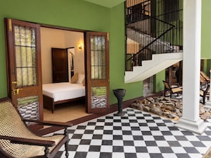 Una habitación con cama, una silla, una escalera y suelo a cuadros.