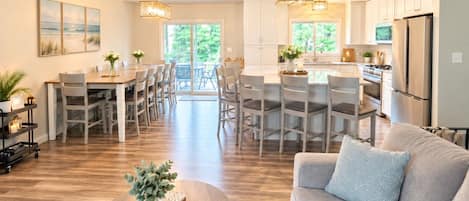 A spacious living area with a sofa, coffee table, and a dining area with chairs and a table.