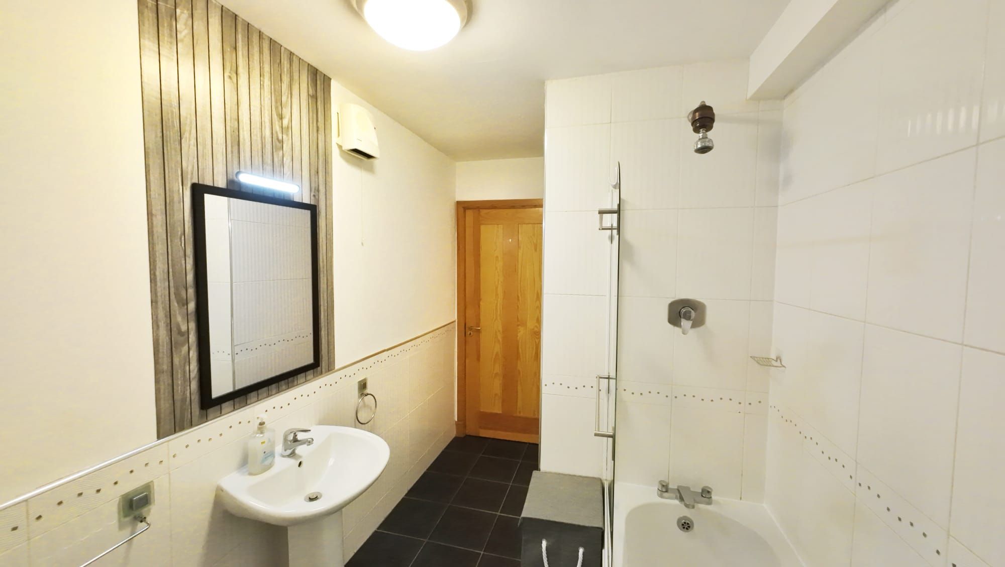 Ein Badezimmer mit Waschbecken, Spiegel, Dusche und Toilette.