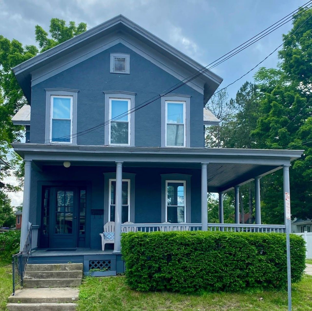 A two-story house with a porch, a front door, and a small front yard.