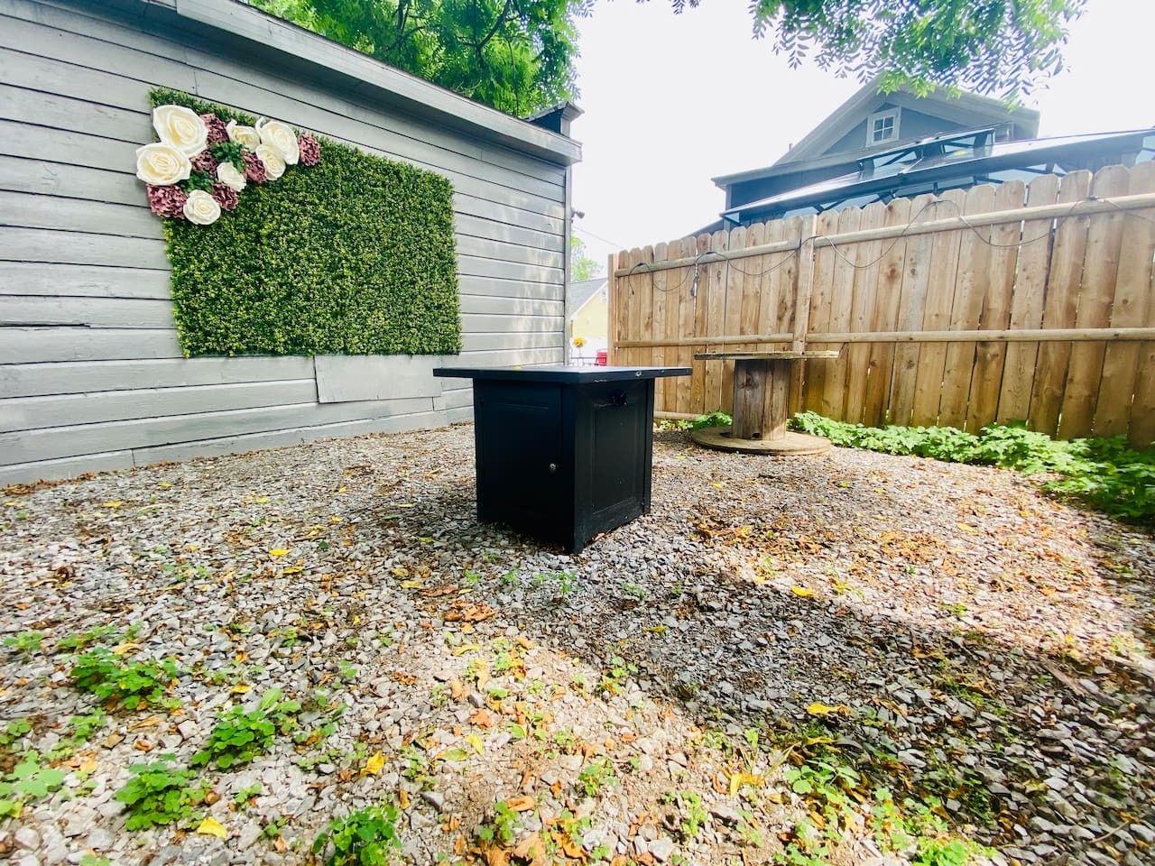 A patio area with a black table, a decorative wall with flowers, and a wooden fence.