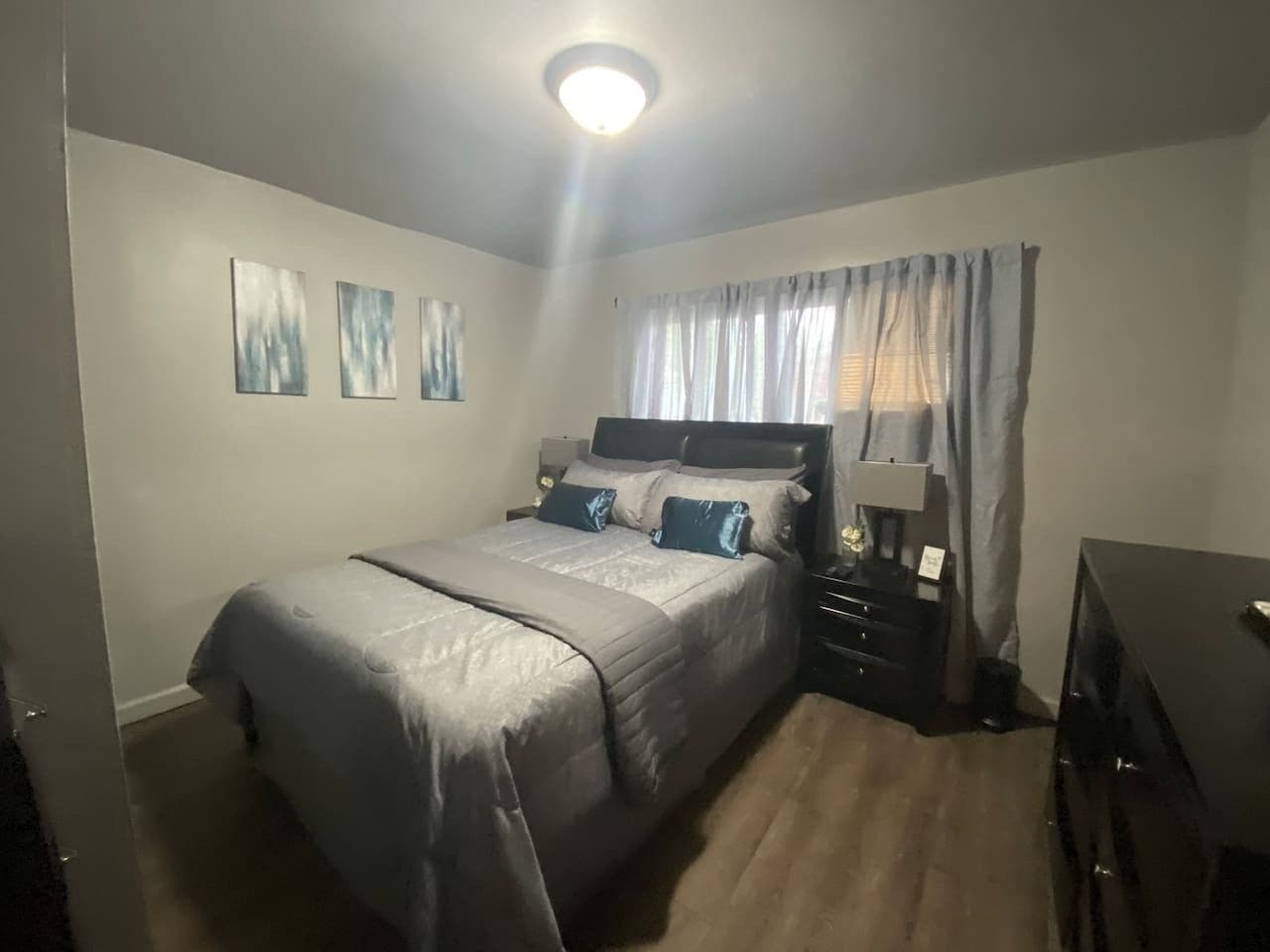 A bedroom with a bed, bedside tables, a lamp, and a window with curtains.