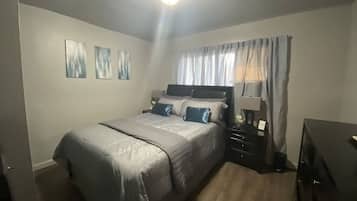 A bedroom with a bed, bedside tables, a lamp, and a window with curtains.
