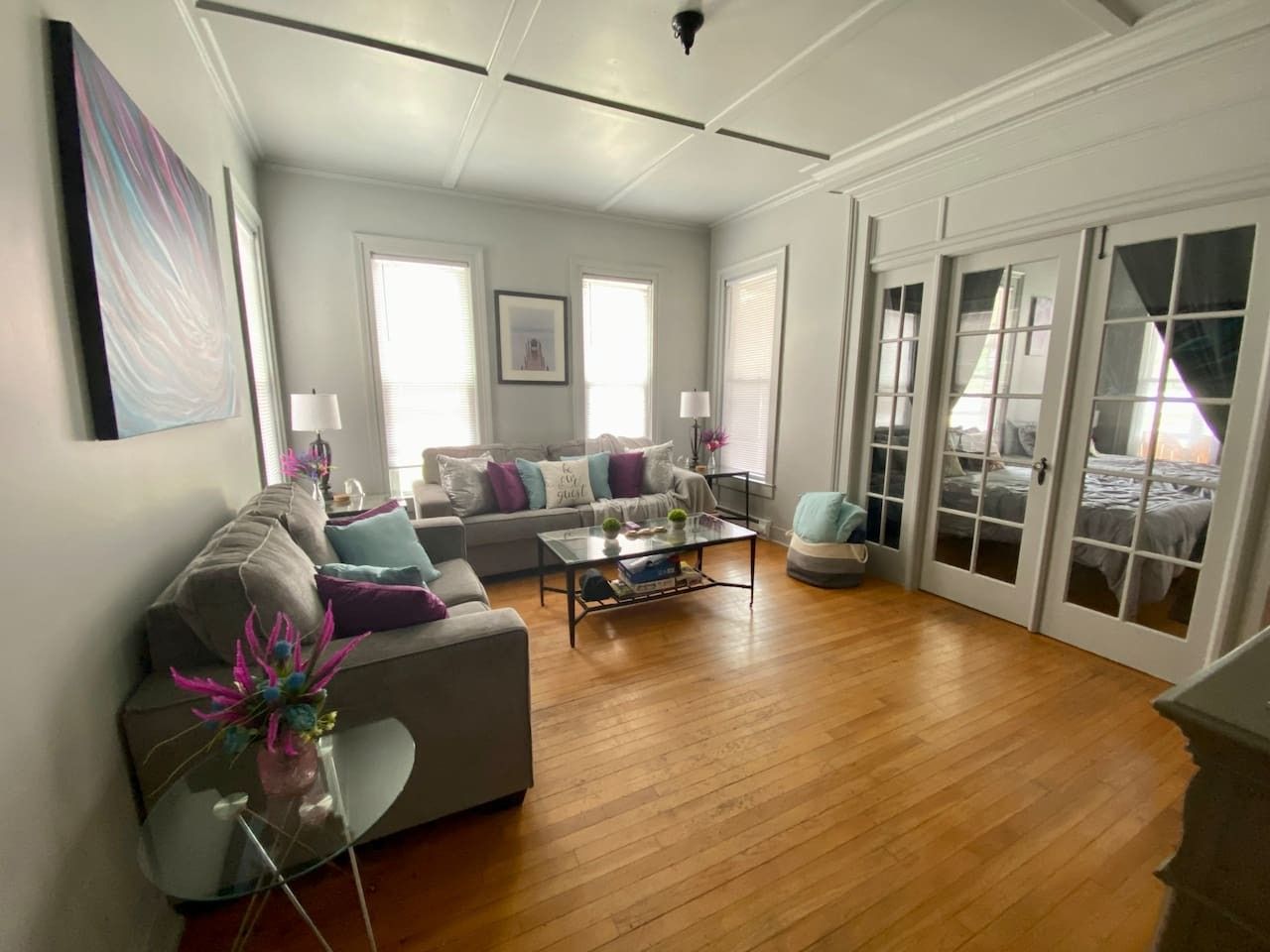 A spacious living room with a sofa, coffee table, and a glass door leading to a balcony.