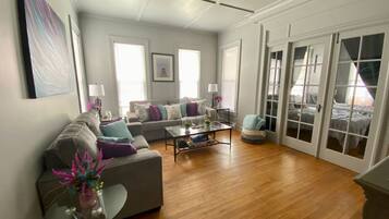 A spacious living room with a sofa, coffee table, and a glass door leading to a balcony.
